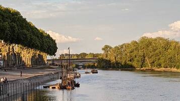 A riverside view with a bridge, docked boats, and a pedestrian walkway.