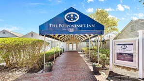 Das Popponeset Inn mit überdachter Eingangspartei, einem Ziegelweg, der zur Tür führt, und einem Schild, das anzeigt, dass es von Freitag bis Sonntag geöffnet ist.