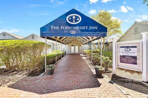 The Popponeset Inn with a covered entrance, a brick pathway leading to the door, and a signboard indicating it's open from Friday to Sunday. - New Rental-3 beds, 2.5 baths, New Seabury (Mashpee)