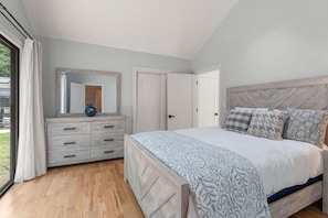 A bedroom with a bed, a dresser, a mirror, and a door. - New Rental-3 beds, 2.5 baths, New Seabury (Mashpee)
