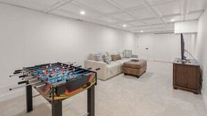 Ein Raum mit Tischfußball, einer Couch, einem Couchtisch und einem Schrank.