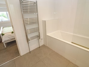 A bathroom with a bathtub, a glass shower enclosure, and a towel rack. - Chy Holly (St Ives)