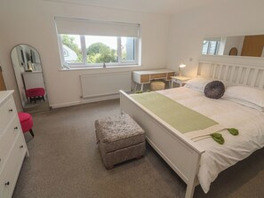 A bedroom with a bed, a desk, a chair, a dresser, a mirror, and a window. - Chy Holly (St Ives)