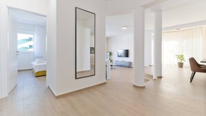 Un'ampia zona giorno con un grande specchio, una TV e un'area pranzo con tavolo e sedie.