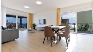 Un soggiorno moderno con zona pranzo, ampie finestre e un balcone con vista.
