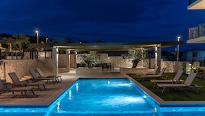 Una piscina con lettini, una zona relax coperta e pareti in pietra.