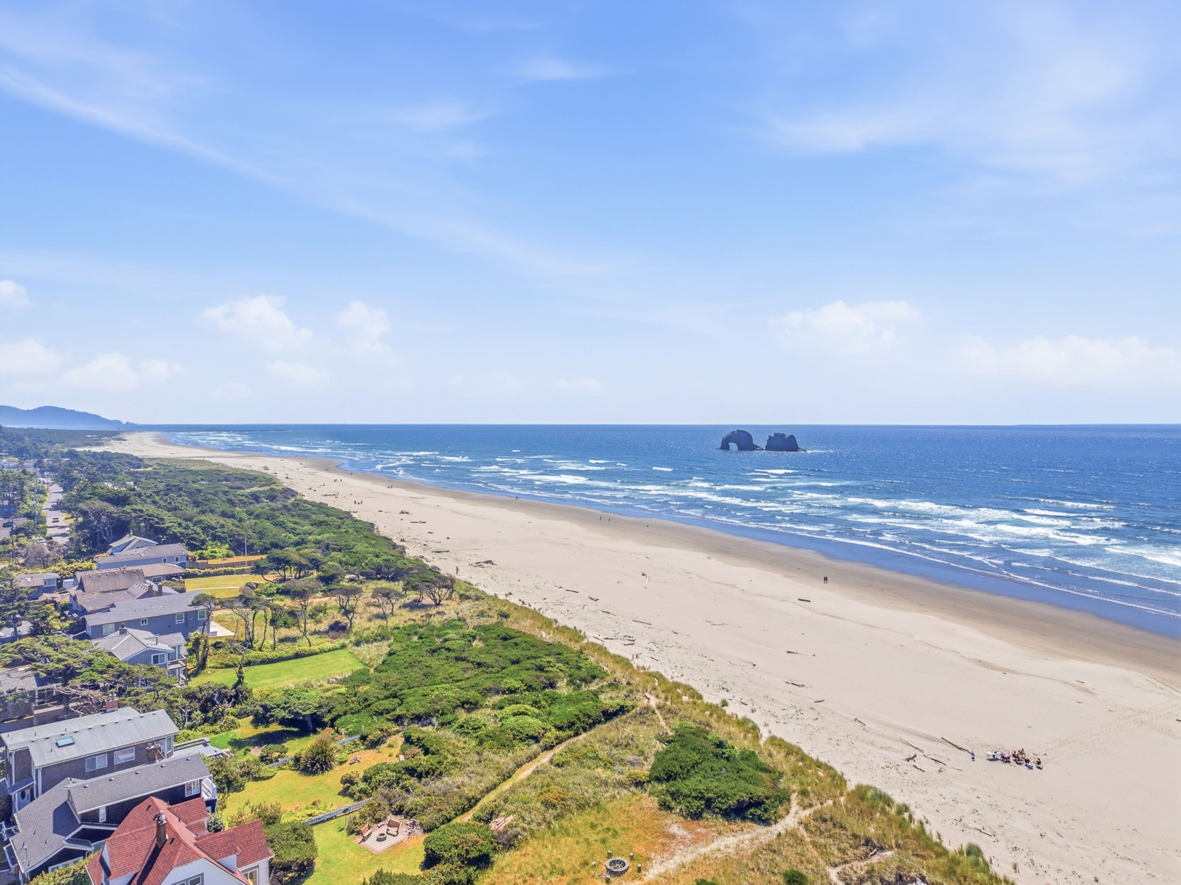 Une vue côtière comprenant une plage, l’océan et une zone résidentielle.