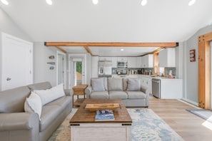 Ein modernes Wohnzimmer mit Sofa, Couchtisch und einer Küche im Hintergrund.