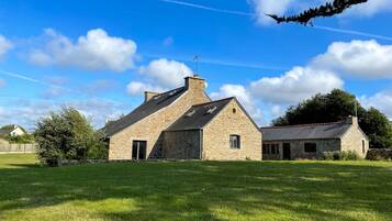 A stone building with a sloped roof, a chimney, and a small window.