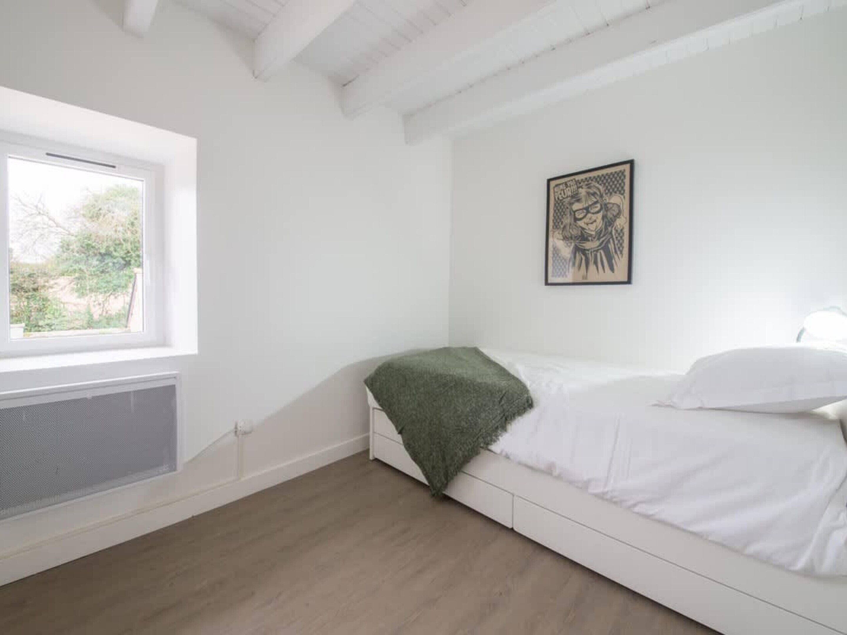 A bedroom with a single bed, a window, and a radiator.