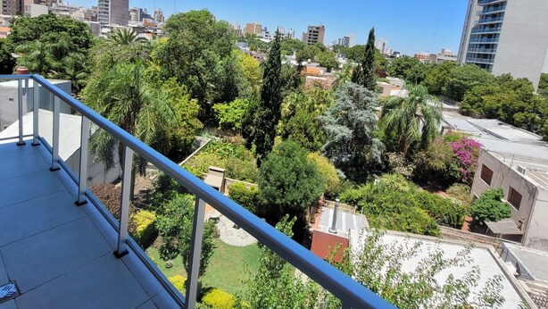 A balcony with a view of a cityscape and greenery.
