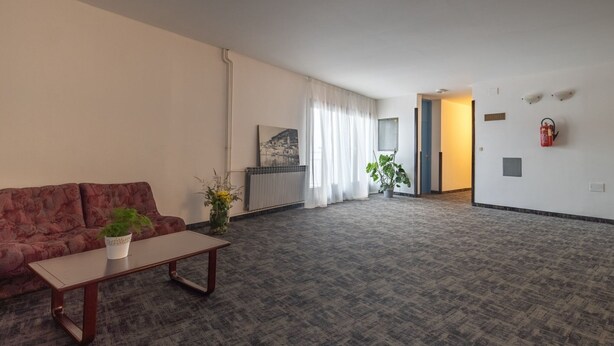 A spacious living room with a sofa, a coffee table, and a potted plant. - Hotel Issa - Triple Room Sea View (Vis)