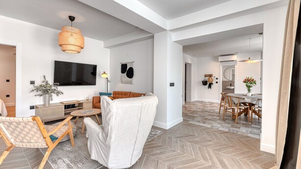 A modern living room with a sofa, TV, and a dining area with a table and chairs. - Apartment With Pool and hot tub (Konavle)