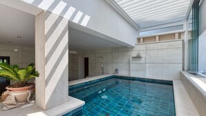 An indoor swimming pool with a tiled floor, a potted plant, and a skylight above. - Apartment With Pool and hot tub (Konavle)