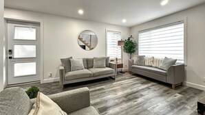 Ein modernes Wohnzimmer mit zwei Sofas, einem runden Spiegel und Holzboden.