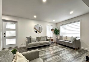 A modern living room with two sofas, a round mirror, and a wooden floor. - The 1568 in Charlevoix (Petite-Rivière-Saint-François)