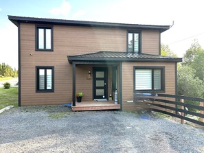 A two-story building with a front porch, a mailbox, and a number '1568' on the door. - The 1568 in Charlevoix (Petite-Rivière-Saint-François)