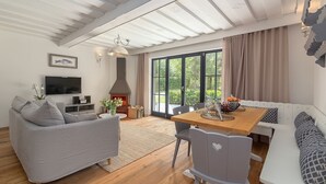 Uma sala de estar moderna com lareira, sofá, mesa de jantar e janelas amplas.