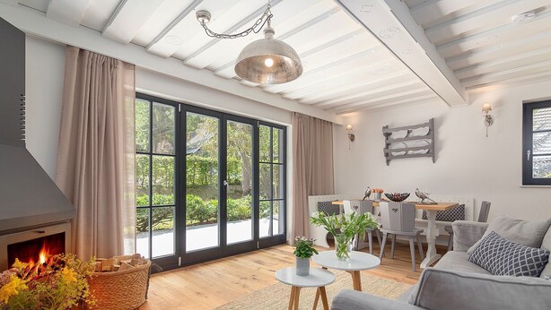 Uma sala de estar espaçosa com lareira, grandes janelas, área de jantar e um ambiente acolhedor.