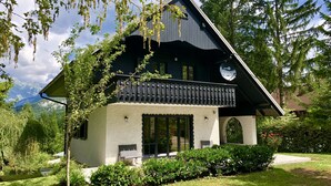 Uma casa em estilo chalé com varanda, janelas amplas e montanhas ao fundo.