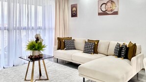 Ein modernes Wohnzimmer mit einer Couch, einem Glastisch, einer Zierpflanze und einem Teppich.