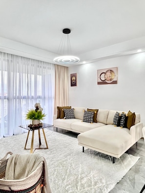 Ein modernes Wohnzimmer mit einem Sofa, einem Glastisch, einer Zimmerpflanze und einem Teppich.