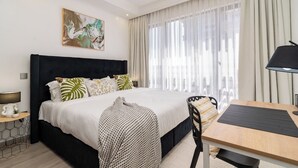 Ein modernes Hotelzimmer mit einem großen Bett, einem Schreibtisch und einem Stuhl.