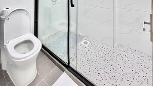 Ein modernes Badezimmer mit einer Duschkabine, Toilette und Handtuchhalter.