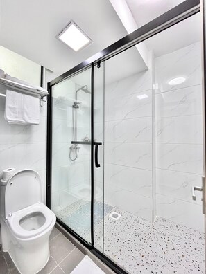 Ein modernes Badezimmer mit einer Duschkabine aus Glas, einer Toilette und einem weißen Waschbecken.
