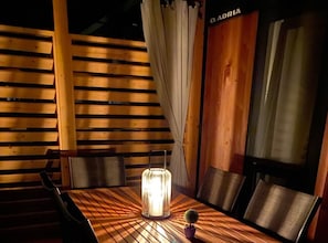 Ein Holztisch mit Stühlen, eine beleuchtete Tischlampe und ein kleiner Blumentopf.