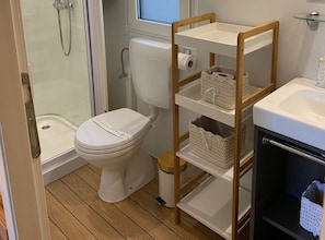 Ein Badezimmer mit Toilette, Dusche und einer Ablage mit Körben.