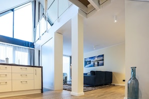 A spacious living area with a high ceiling, a modern kitchen, and a large window. - Appartements im Maremuritz Yachthafen Resort (Waren (Müritz))
