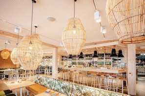 A modern interior with hanging wicker chandeliers, a bar area with stools, and a seating area with patterned cushions. - Appartements im Maremuritz Yachthafen Resort (Waren (Müritz))