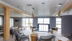 Un vaste espace intérieur aménagé avec des meubles modernes, une piscine et de grandes fenêtres.