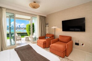 A hotel room with a bed, two armchairs, a TV, and a view of a cityscape through a glass door. - Oceanfront * Patio * Full Generator * Pool * OSJ (San Juan)