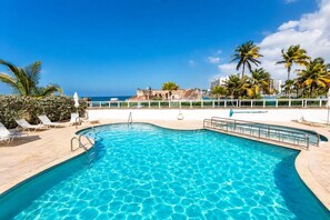 A clear blue pool with a poolside area, including lounge chairs and a view of the ocean. - Oceanfront * Patio * Full Generator * Pool * OSJ (San Juan)