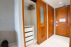 Ein Flur mit einem weißen Schrank, Holztüren mit Lamellen und einem Fliesenboden.