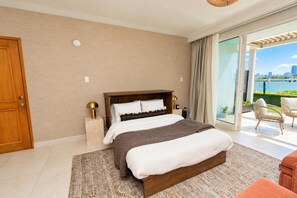 Ein Schlafzimmer mit einem großen Bett, einem Holzkopfende, einem Nachttisch mit Lampe und Blick auf eine Stadtlandschaft durch eine Glastür.