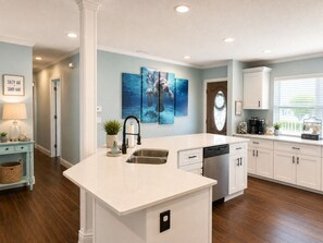 A modern kitchen with a central island, white cabinetry, and a large window providing natural light. - Crystal River waterfront oasis w/floating dock 3BR/3BA house, large heated pool (Crystal River)