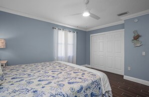 A bedroom with a bed, a ceiling fan, a white door, and a blue wall. - Crystal River waterfront oasis w/floating dock 3BR/3BA house, large heated pool (Crystal River)