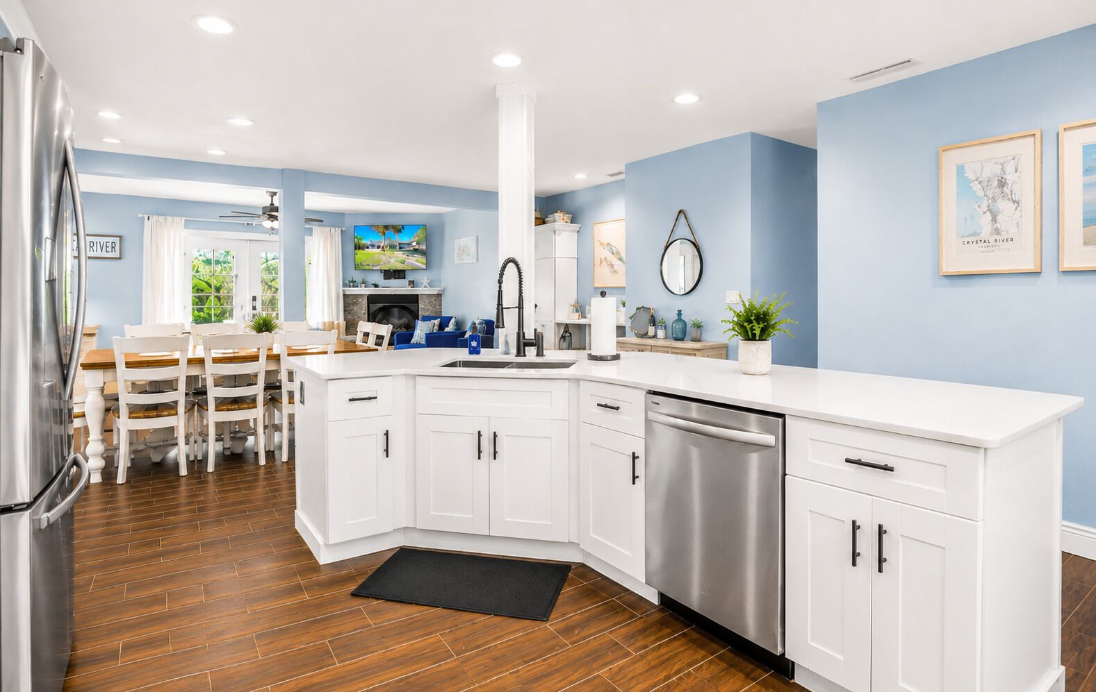 A modern kitchen with white cabinetry, a stainless steel dishwasher, and a black doormat.