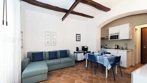 Un accogliente soggiorno con divano, un tavolo da pranzo con sedie, una cucina con forno a microonde e un soffitto con travi a vista.
