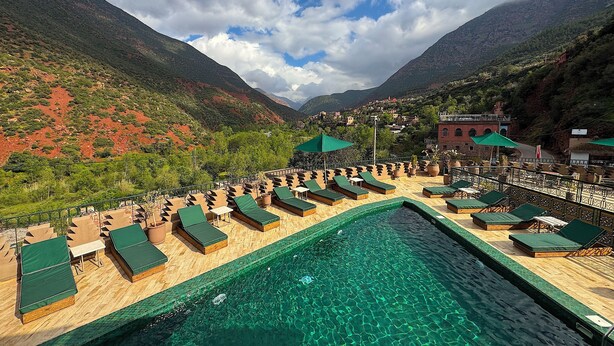 Zona de piscina con sillas de descanso y vistas a un paisaje montañoso.