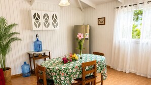 A dining area with a table set for four, a refrigerator, and a large water dispenser. - Cabañas Anariki - Cozy centrally located room with 2 single beds #2 (Hanga Roa)