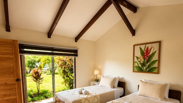 A bedroom with two beds, wooden beams, a large window, and a tropical plant. - Cabañas Anariki - Cozy centrally located room with 2 single beds #2 (Hanga Roa)