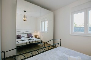 Ein Schlafzimmer mit Bett, Fenster, Spiegel und einer Pendelleuchte.