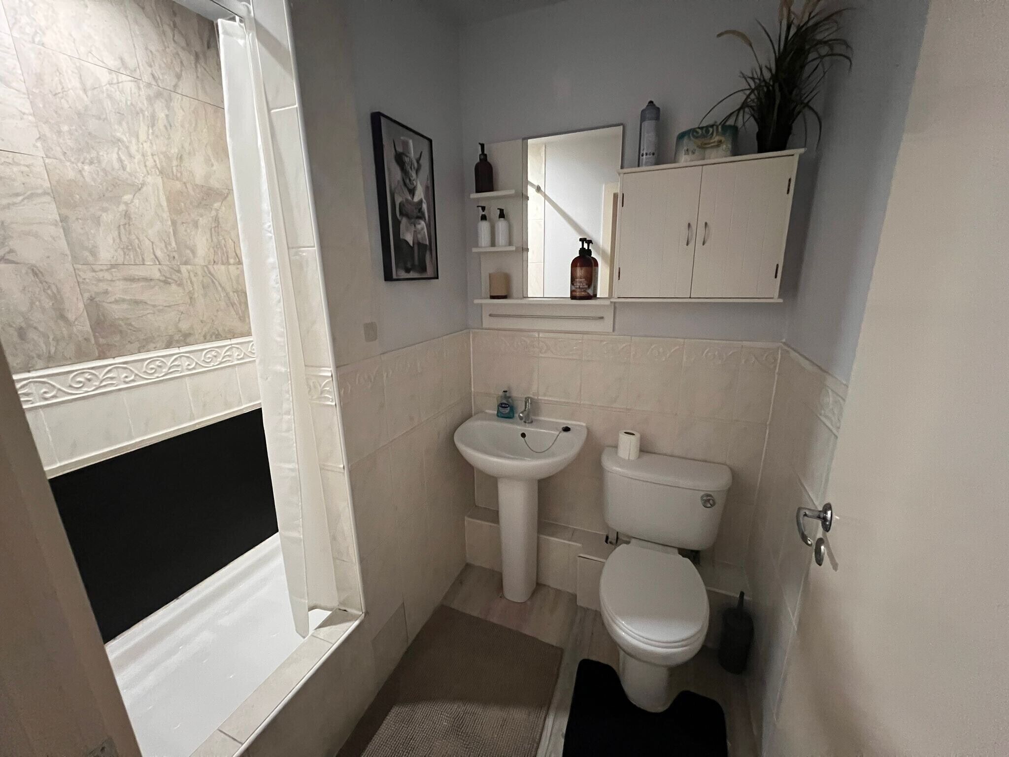 A bathroom with a bathtub, sink, toilet, and a mirror above the sink.