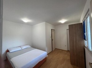 Ein Schlafzimmer mit einem Bett, einem Holzschrank, einer Tür und einem Fenster.