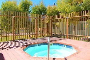 Ein Whirlpool mit Holzterrasse und einer ihn umgebenden Holzzahlung.
