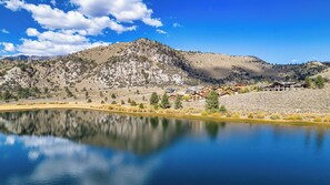 Blick auf einen See mit Bergen, einschließlich eines Resorts mit mehreren Gebäuden und Holzbauten unter klarem Himmel.